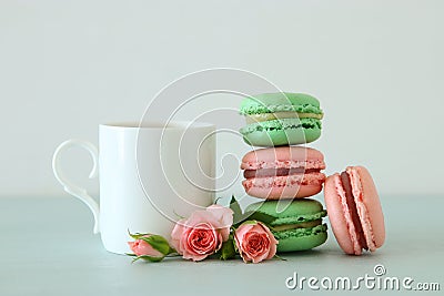 White vintage cup of coffee and colorful macaron or macaroon over pastel wooden table. Stock Photo