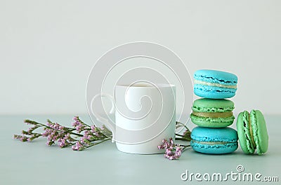 White vintage cup of coffee and colorful macaron or macaroon over pastel wooden table. Stock Photo