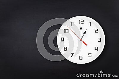 White wall clock on black chalkboard background. One 1 a.m. or 1 p.m. Stock Photo