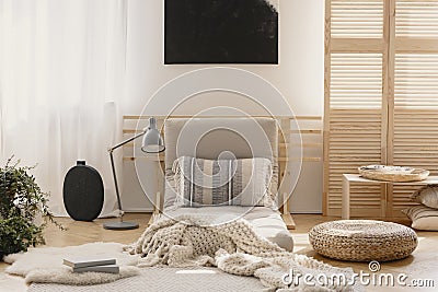 White warm blanket and patterned pillow on beige futon in stylish natural bedroom interior, real photo with mockup on the empty Stock Photo