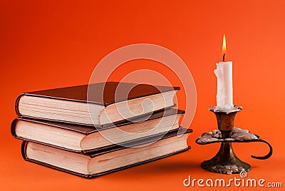 Mystical Illumination: Burning Candle and Vintage Books in Halloween Ambiance Stock Photo