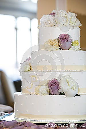 White wedding cake with yellow, white, and purple flowers. 4 tiers - wedding cake series Stock Photo