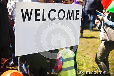 White Welcome sign in the street. Blurred people visiting an event in the city Stock Photo