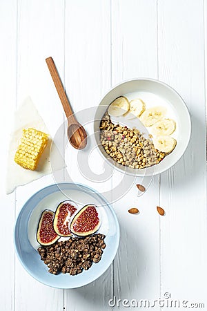 white wheat and chocolate granola with low-fat yogurt in a white bowl in a composition with a spoon, honeycombs, banana fig on Stock Photo