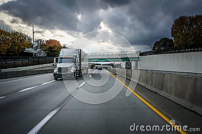 White 18 wheeler semi-truck on highway with storm clouds in the sky Stock Photo