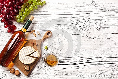 White wine bottle, grape, cheese and wineglass on white wooden board Stock Photo