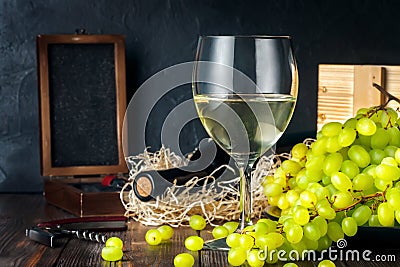 White wineglass and white yellow green bunches of berry grapes with bottle Stock Photo