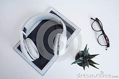 White wireless on a white tablet, glasses and a flower on a white table. Stock Photo