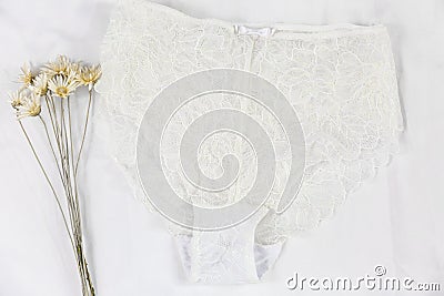 White women lace underlace and flowers on the bed. Top view, flat lay. Stock Photo