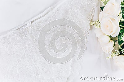 White women lace underlace and flowers on the bed. Top view, flat lay. Stock Photo