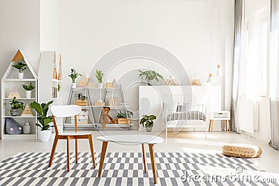 White wooden chair and table set, green plants in a spacious, sunlit teenager bedroom interior with scandinavian decor Stock Photo