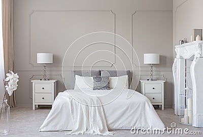 White wooden fireplace portal in bright bedroom interior, copy space on empty grey wall Stock Photo