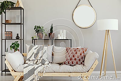 White wooden lamp next to stylish scandinavian couch with patterned pillow in elegant living room interior Stock Photo