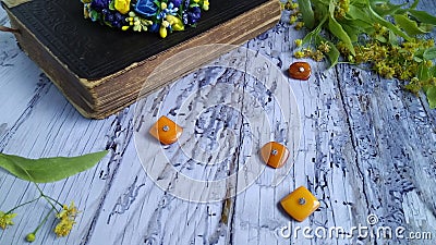On a white wooden table are scattered pieces of natural amber, the vintage Christian Bible Sacred writings and linden flowers.. Stock Photo