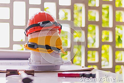 White, yellow and orange hard safety, helmet hat for safety project of workman or engineer on desk and construction plans with on Stock Photo