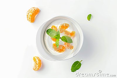 White yogurt with tangerines and green leaves - healthy food on white background with copy space Stock Photo