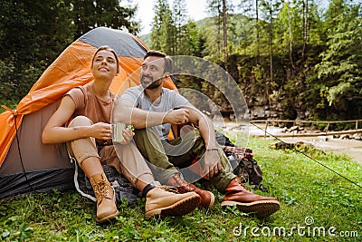 Young travelers resting in tents while hiking in green forest Stock Photo