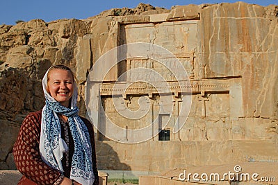 Young woman tourist with a head covered stands on the background of the famous bas-reliefs of the day capital of Persia Iran - P Stock Photo