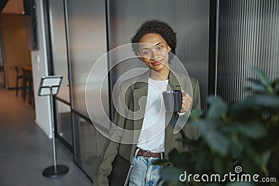 A whitecollar worker is standing in a hallway holding a cup of coffee Stock Photo