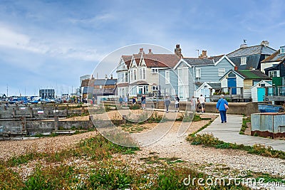 Tourists and locals walk along the wooden seafront pathway in front of the distinctive architecture Editorial Stock Photo