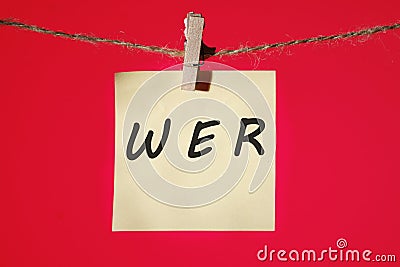 Who, German word for Who, (German: Wer) text on a yellow sticker hanging on a rope with clothespins on a red background Stock Photo