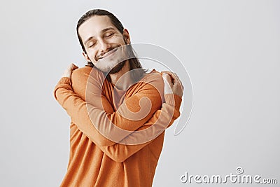 Who need girlfriends if you can hug yourself. Funny playful european guy with long hair and beard cuddling himself and Stock Photo