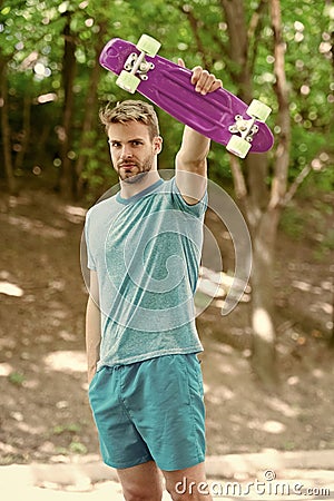 Who want to learn extreme trick. Guy carries penny board ready to ride. Man serious face carries penny board park nature Stock Photo