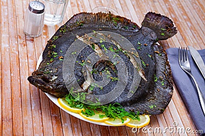 Baked brill fish with lemon and greens Stock Photo