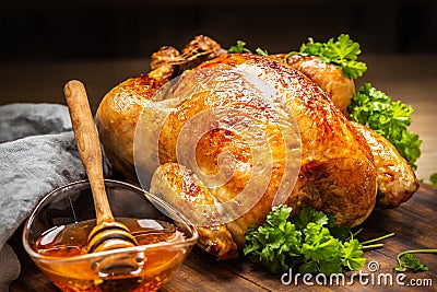 Whole baked chicken with crusty skin glazed with honey on top and parsley on the side Stock Photo