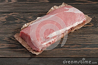 Whole boneless pork loin without fat. Pork tenderloin on paper on a dark background Stock Photo