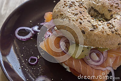 Whole Grain Bagel with salmon, cream cheese, onions and kosher pickle Stock Photo