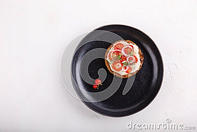Whole grain bread sandwich with tomatoes and onion, seasoned with black pepper on black plate Stock Photo