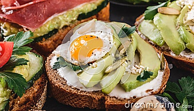 Whole grain bread sandwiches with fried quail egg, avocado, herbs and seeds on black background. Clean eating, healthy vegan Stock Photo