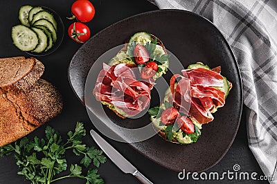 Whole grain bread sandwiches with prosciutto, avocado, cucumber, tomatoes Stock Photo