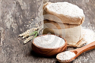 Whole grain flour in a wooden bowl and sackcloth bagwith ears Stock Photo