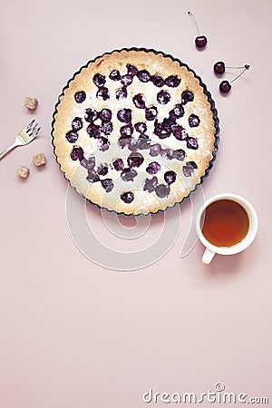 Whole homemade cherry cake on pastel pink background with fresh berries and cup of tea Stock Photo