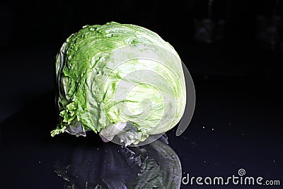 Whole iceberg Salad on black reflective background Stock Photo