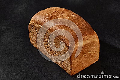 Whole loaf of fresh, palatable baked white bread against black background with copy space. Close-up Stock Photo