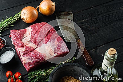 A whole piece of raw Beef Brisket,with ingredients for smoking making barbecue, pastrami, cure, on black wooden table background Stock Photo