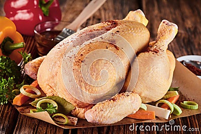 Whole raw seasoned chicken with fresh vegetables Stock Photo