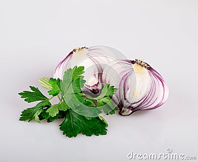 A whole red flat bulb in the skin and half an onion with leaves of fresh young parsley, isolated on a white background Stock Photo