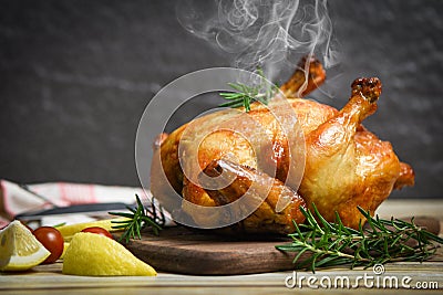 Whole roasted chicken rosemary and tomato lemon on wooden cutting board - Baked chicken grilled barbecue delicious food on dining Stock Photo