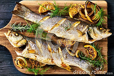 Roasted sea bass on a black wooden table, close-up Stock Photo