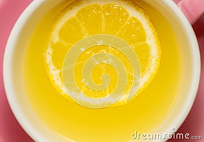 A whole slice of lemon floating in tea or lemonade in a pink mug Stock Photo