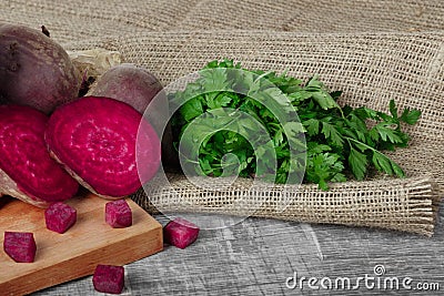 Whole and sliced beetroots and fresh parsley on a light cloth and on a wooden background. Vegetables from a garden. Stock Photo