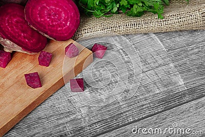 Whole and sliced beetroots and fresh parsley on a light cloth and on a wooden background. Vegetables from a garden. Stock Photo