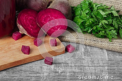 Whole and sliced beetroots, parsley and beverage on a cutting board and on a wooden background. Vegetables from a garden Stock Photo