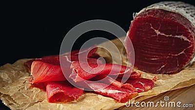 Whole and sliced bresaola on paper on a cutting board Stock Photo