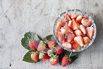 Whole and sliced piece strawberry fruit in bowl on brown wooden table. Stock Photo