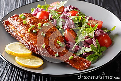 Whole spicy fried sea perch served with fresh vegetable salad close-up in a plate. horizontal Stock Photo